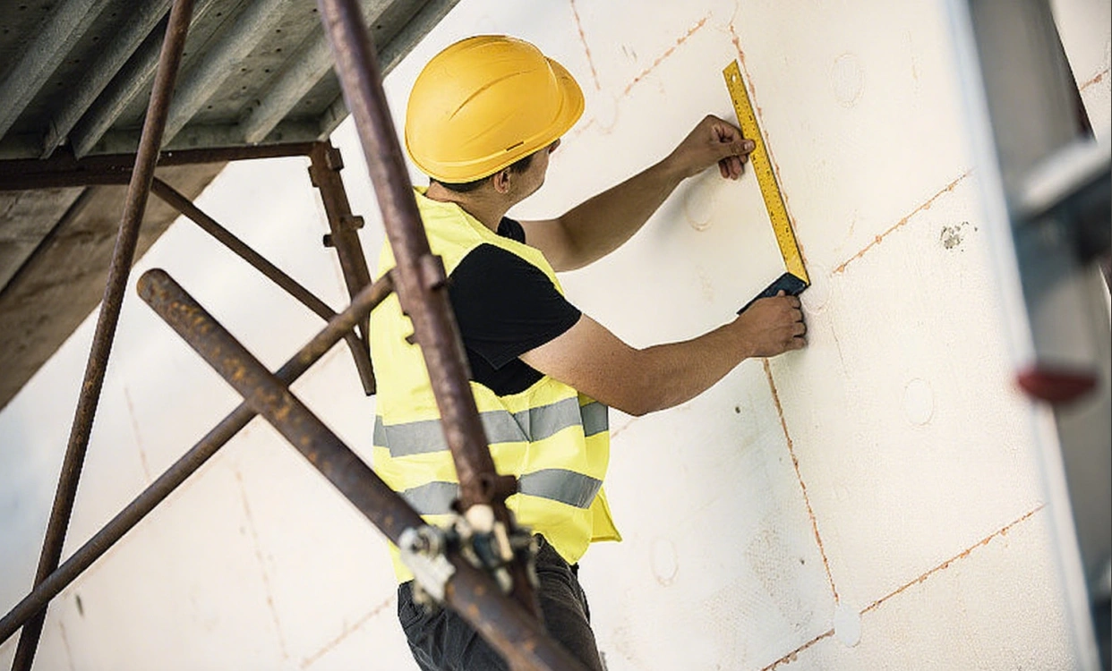 A construction worker is taking measurements