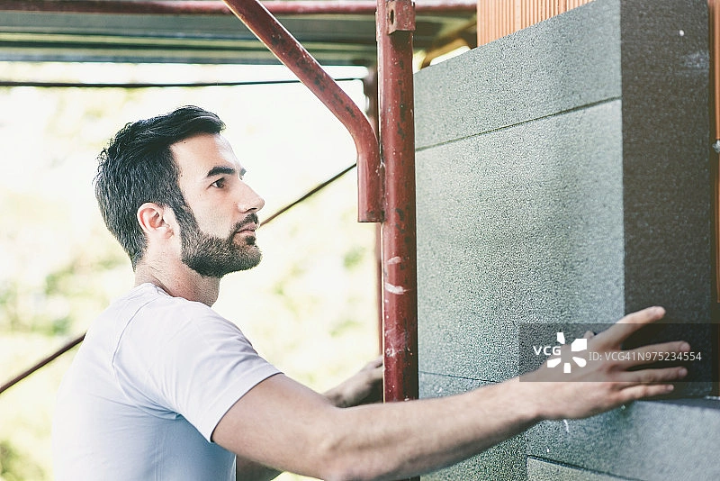Worker Installing Thermal Insulation Panels in Building Construction